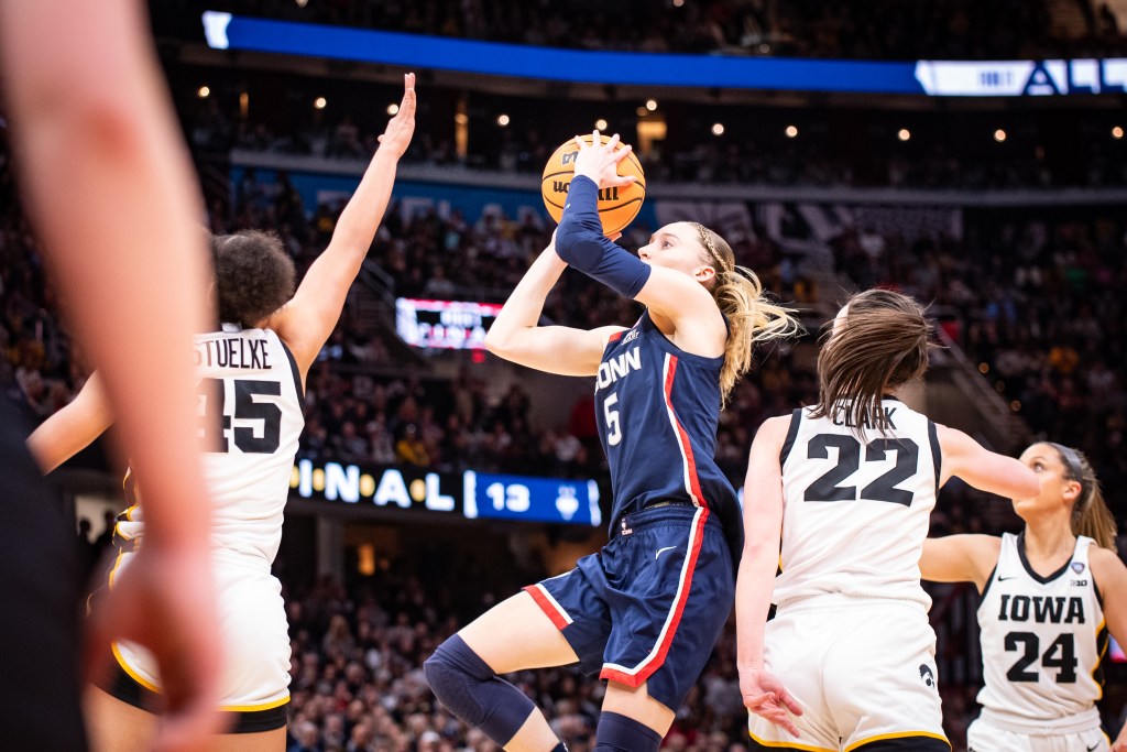 UConn guard Paige Bueckers goes up for a right-handed shot surrounded by Iowa defenders.