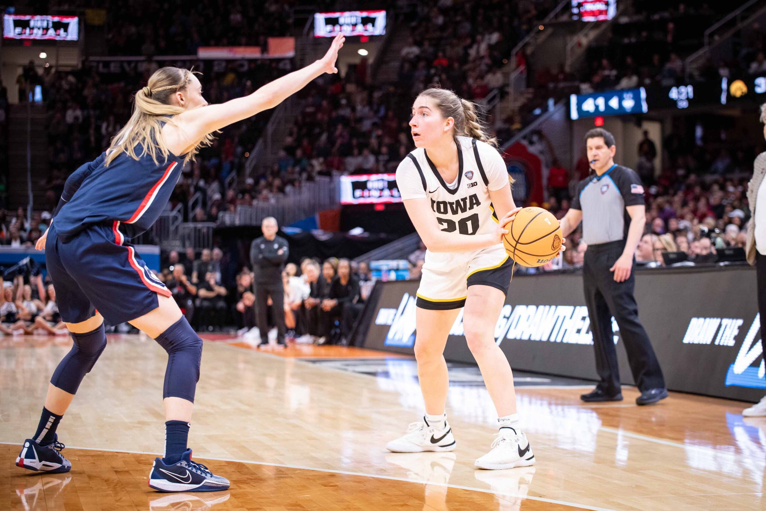 Iowa guard Kate Martin holds the ball on the left side of her body near the sideline. Her eyes are up as she scans the court, looking for passing options.