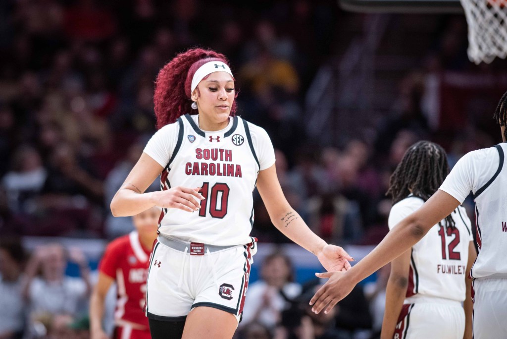 South Carolina center Kamilla Cardoso extends her arm down to low-five a teammate.