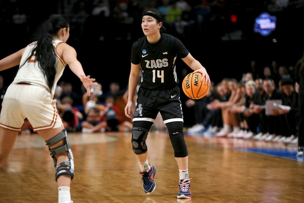 Gonzaga guard Kaylynne Truong dribbles the ball with her left hand on the perimeter. A Texas defender is in a defensive stance with her arms stretched wide.