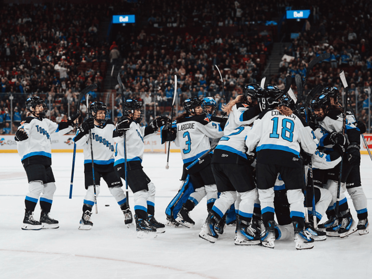 Toronto players celebrate their overtime win over Montréal with a team-wide group hug. They are all in white.