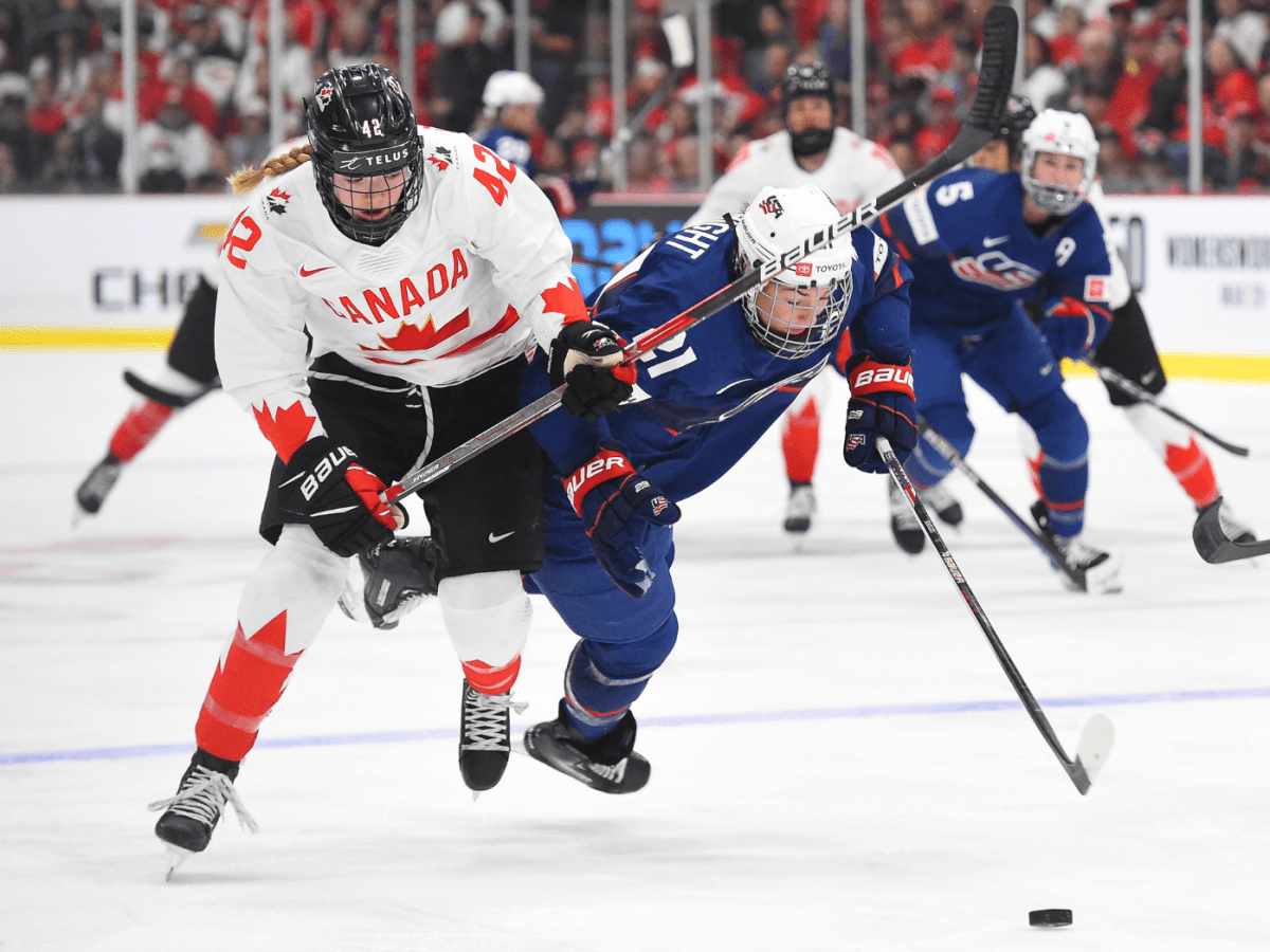 Thompson (left in white) battles Knight (right in blue), who is falling forward, for the puck. Knight currently possesses it.