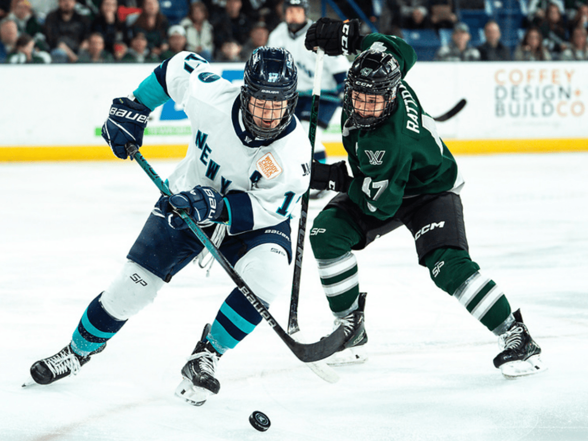 Rattray (right in green) attempts to get the puck from Shelton (left in white). Rattray is preparing to poke it away.