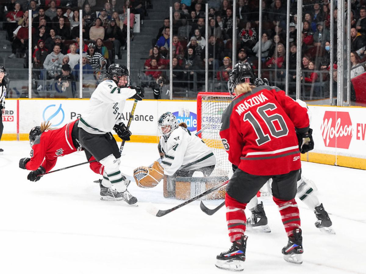 Frankel makes a save from her knees, with a Boston and Ottawa player in front of her and another pair to her left.