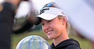 Nelly Korda holds a trophy and smiles