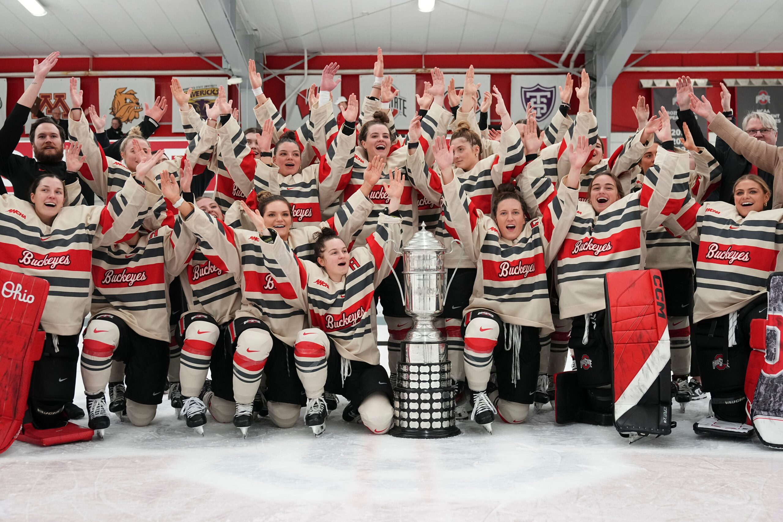 Ohio State women's hockey team celebrates a championship in front of a trophy