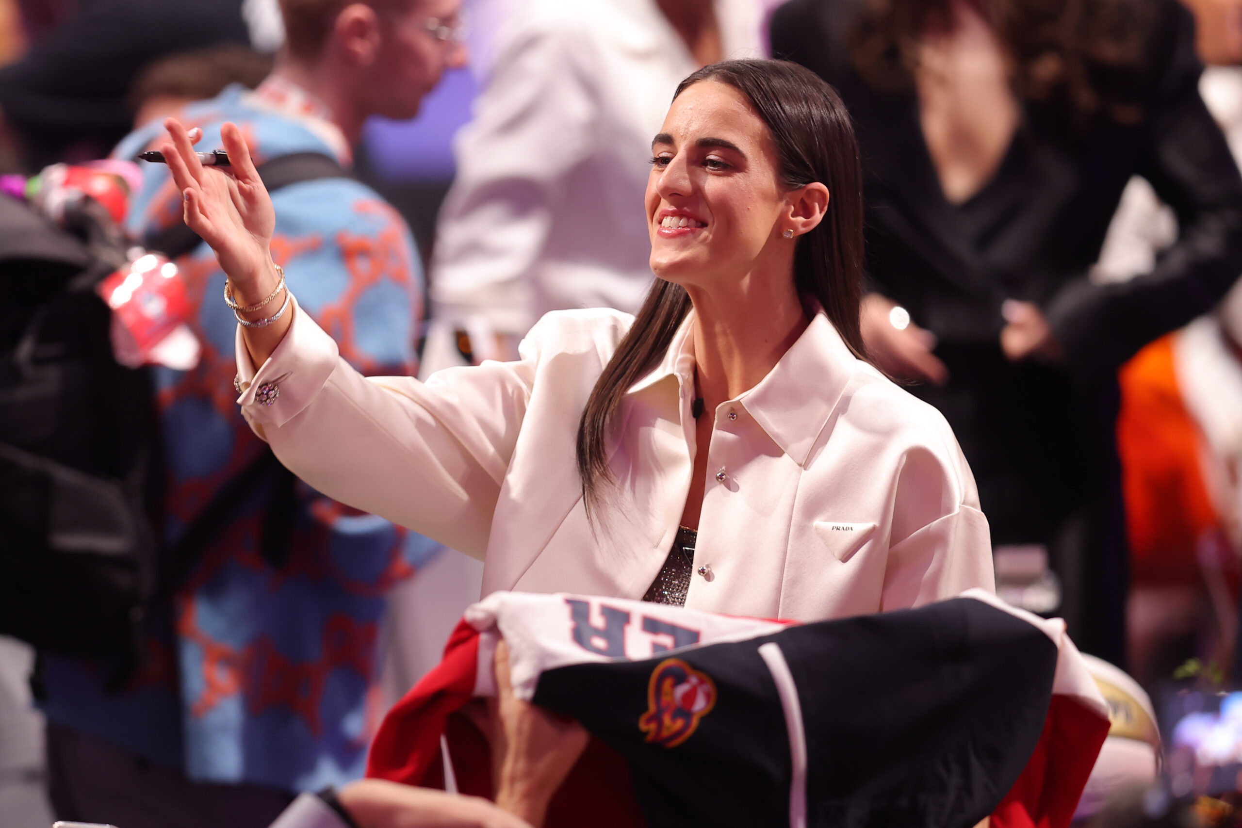 Caitlin Clark looks towards fans as she signs autographs on the orange carpet before the 2024 WNBA Draft