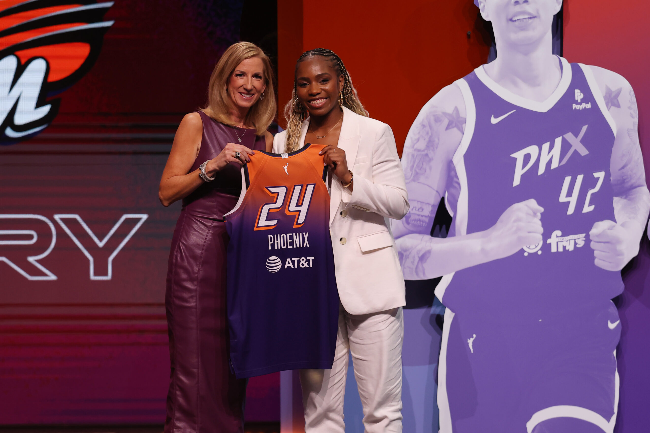 Charisma Osborne and WNBA Commissioner Cathy Engelbert smile and pose for a photo with Osborne's Phoenix Mercury jersey during the 2024 WNBA Draft.