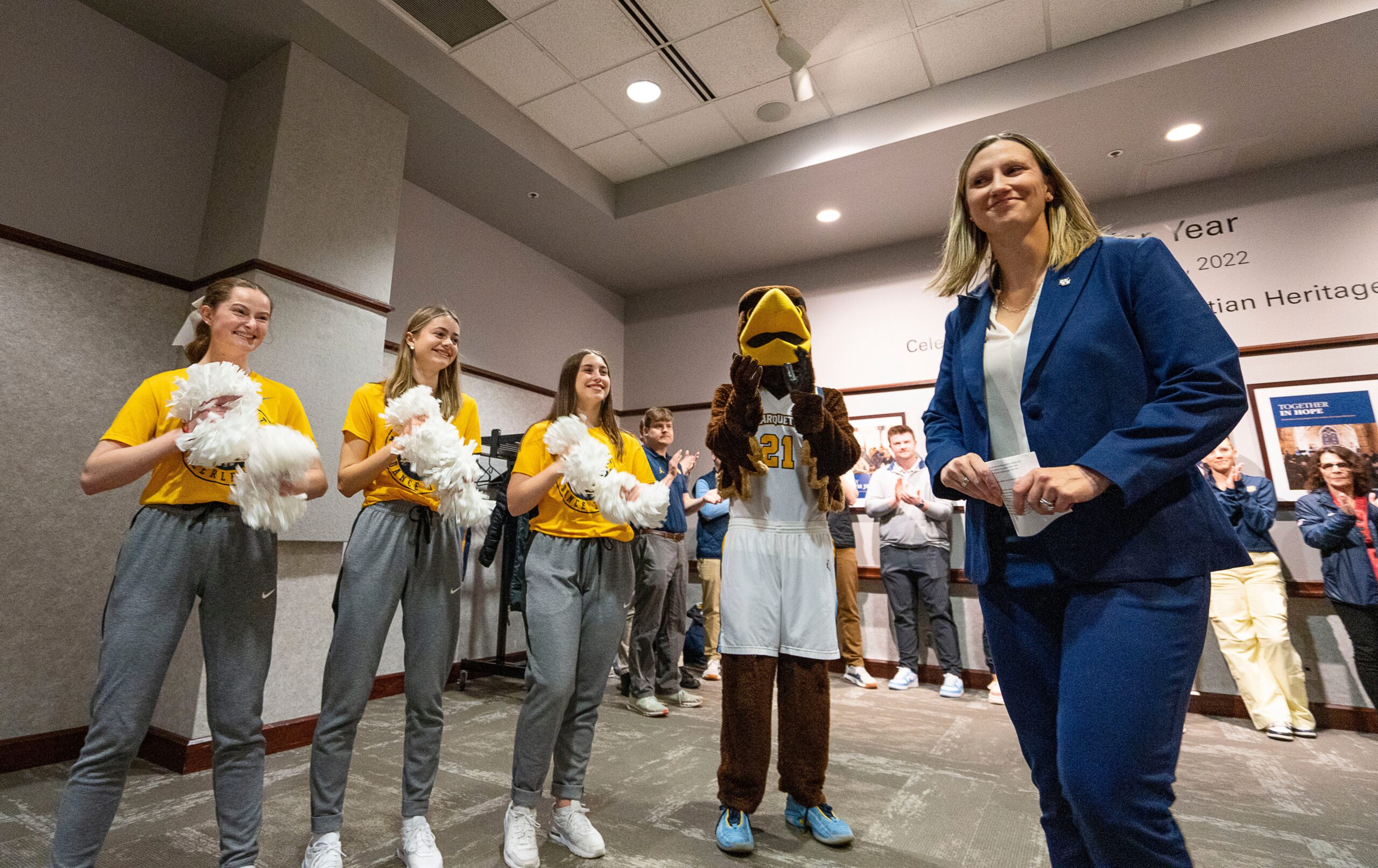Cara Consuegra arrives for introductory press conference at Marquette with cheer leaders and school mascot in the background