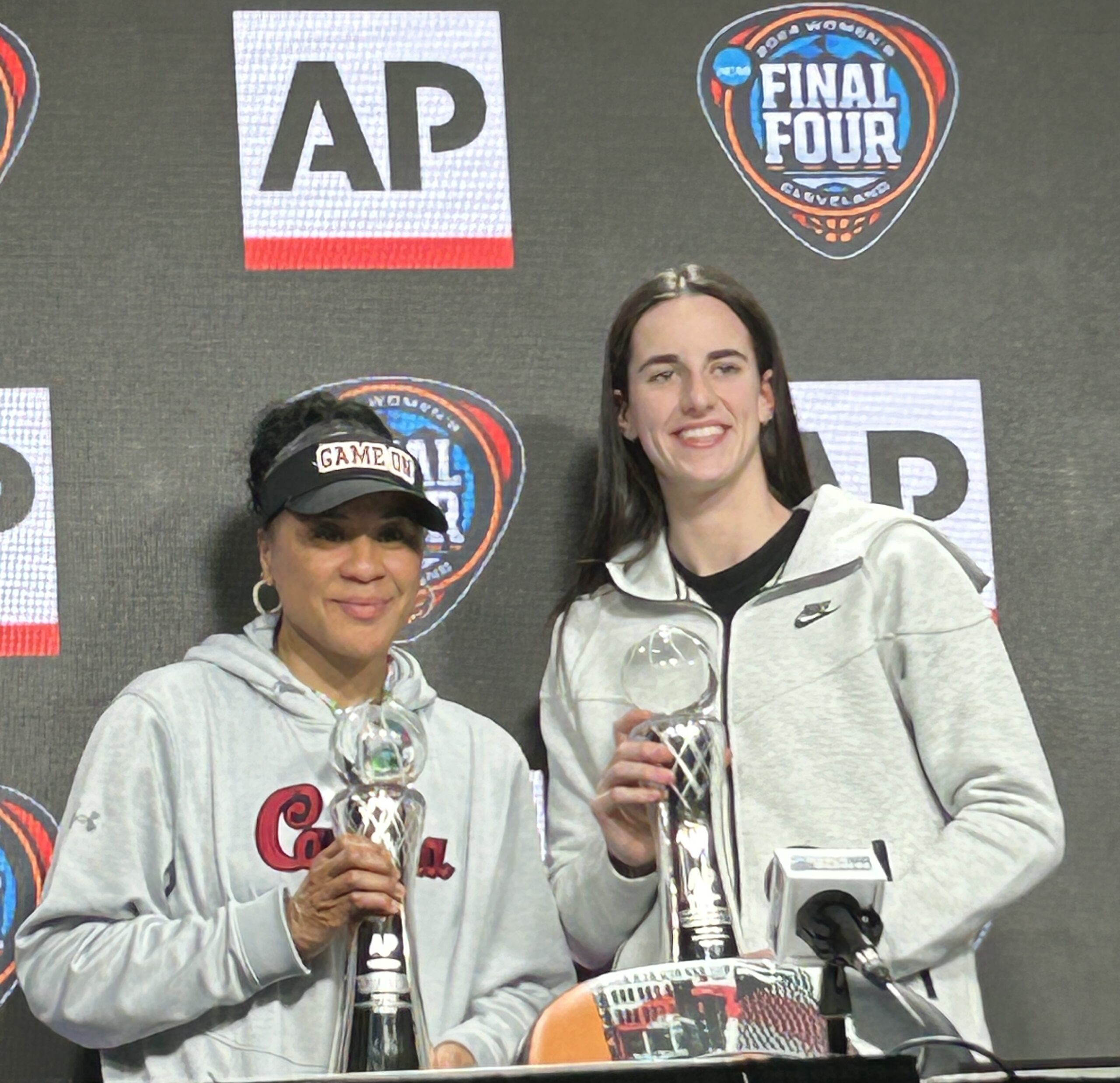 Dawn Staley and Caitlin Clark pose with trophies.