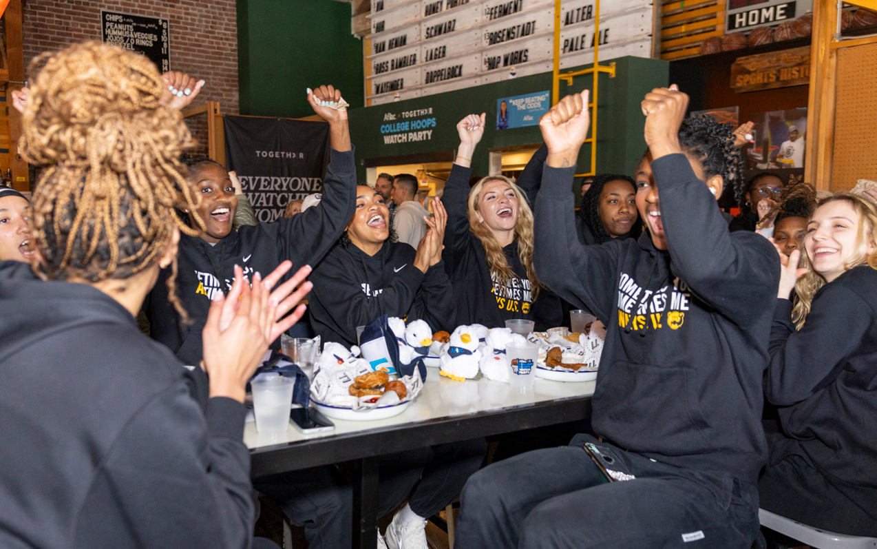 Fans cheer as they watch NCAA Tournament games at a Togethxr pop-up sports bar event.