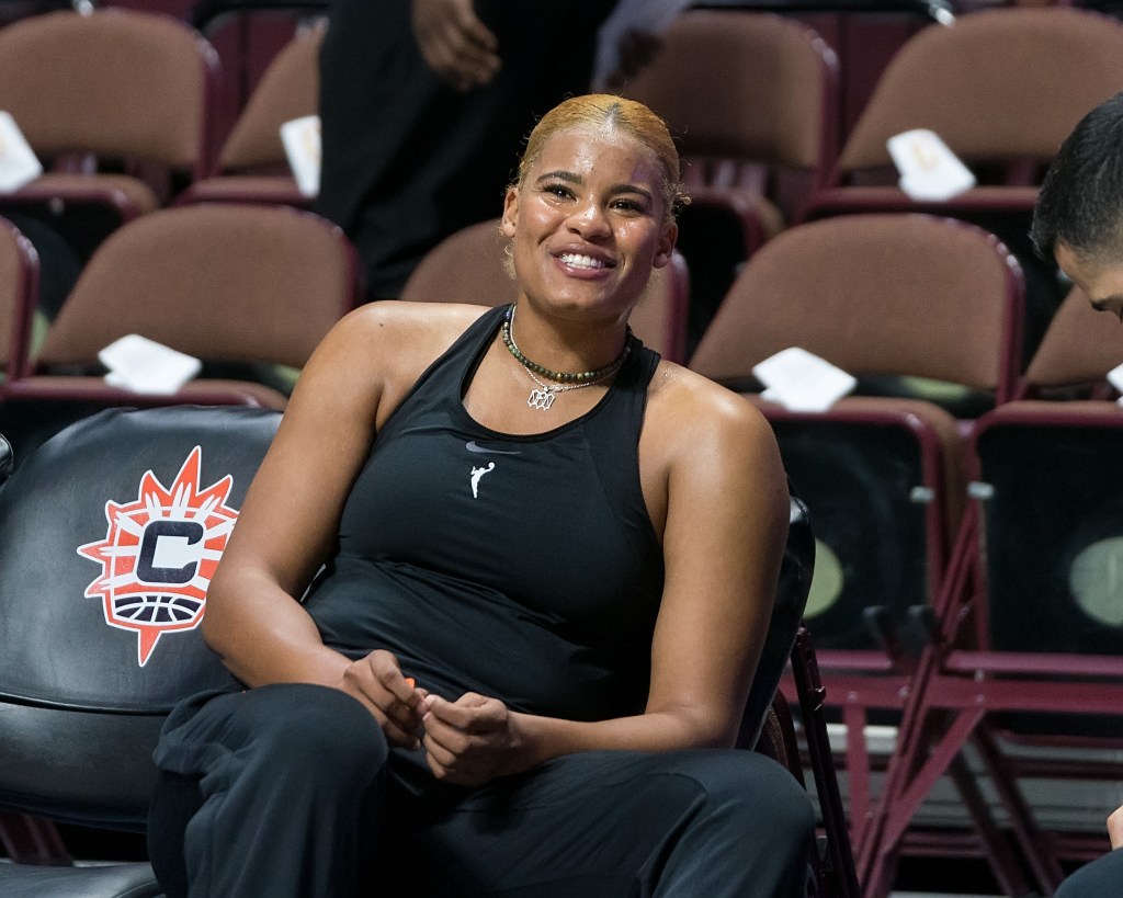 Nyara Sabally smiles while sitting on the bench. 