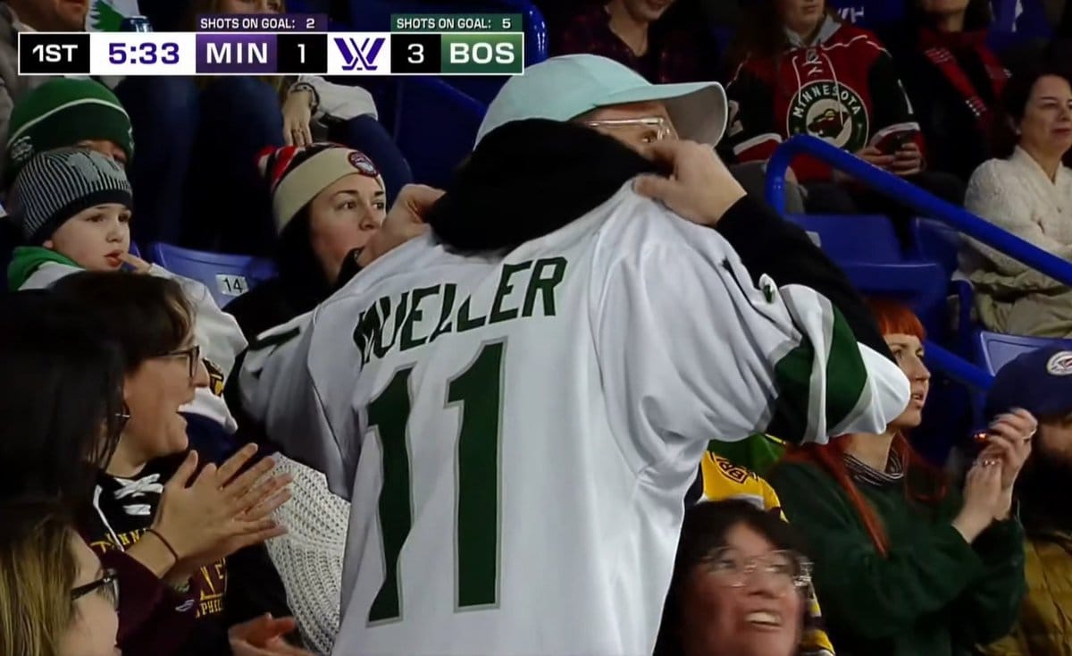 A man in a teal baseball cap with his back towards the camera, showing off a white #11 Müller jersey from the preseason. It is unique because her name is spelled with "ue" instead of a u with a umlat.
