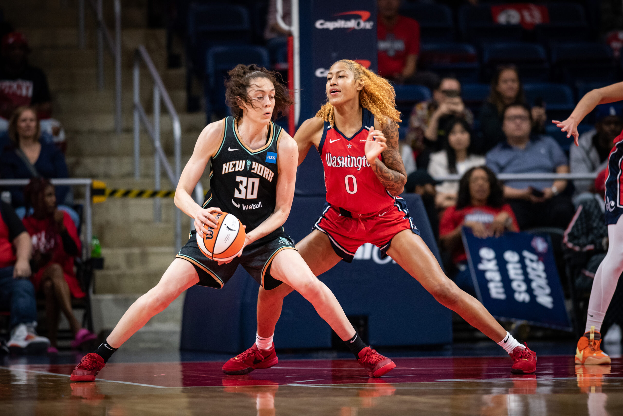 Washington Mystics center/forward Shakira Austin has her feet in a wide base and her body squared up to defend New York Liberty forward Breanna Stewart, who operates in the post with her back to the basket.