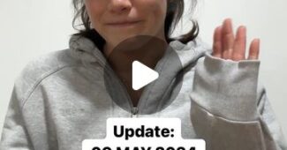 A screenshot of a video by Georgia Godwin of Australia. In the video, she wears a gray sweatshirt, sits at a table and waves to the camera with her left hand.