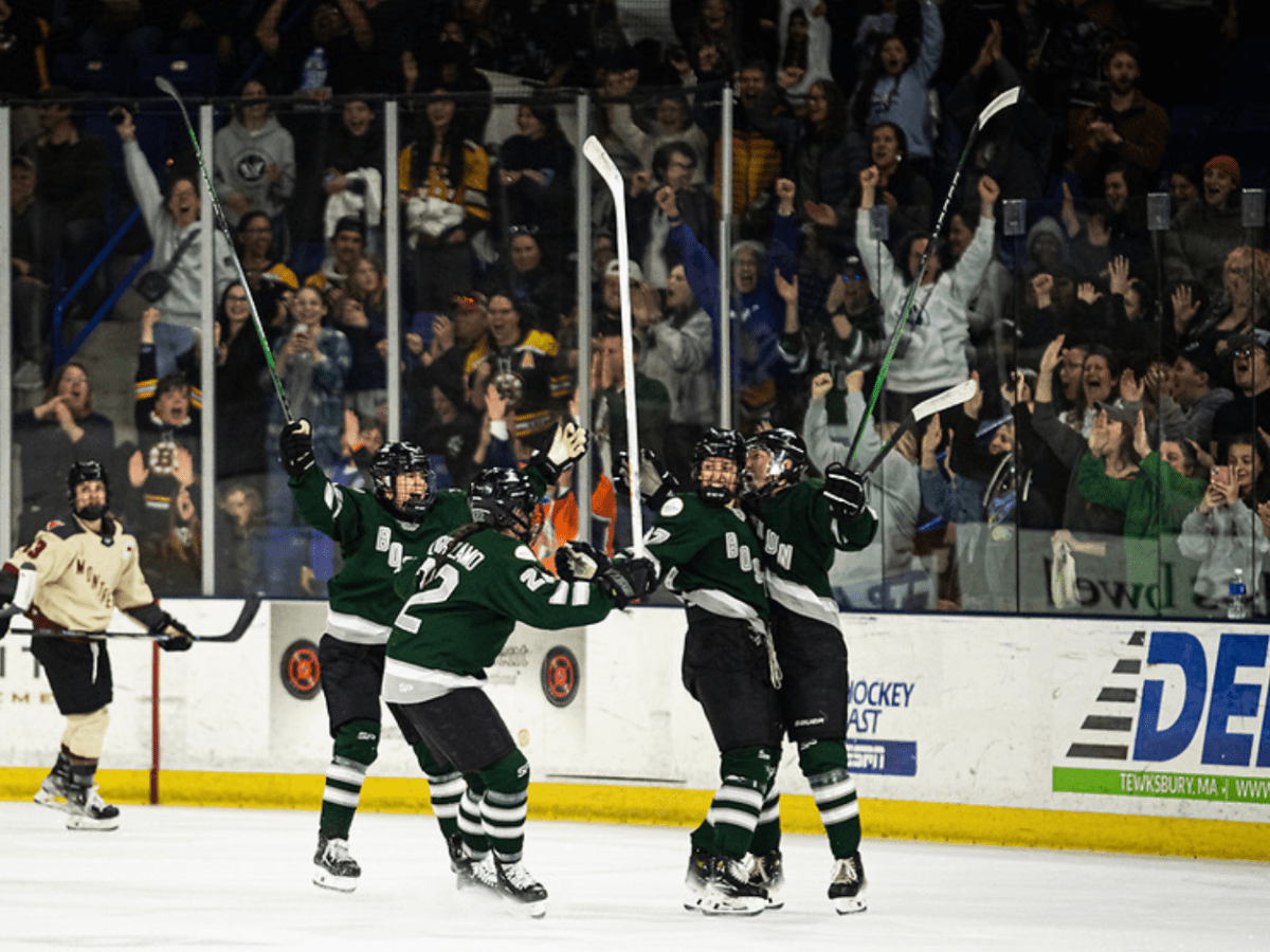 Three Boston players go in for a group hug with Fratkin after she scored. They're smiling and wearing green home uniforms.