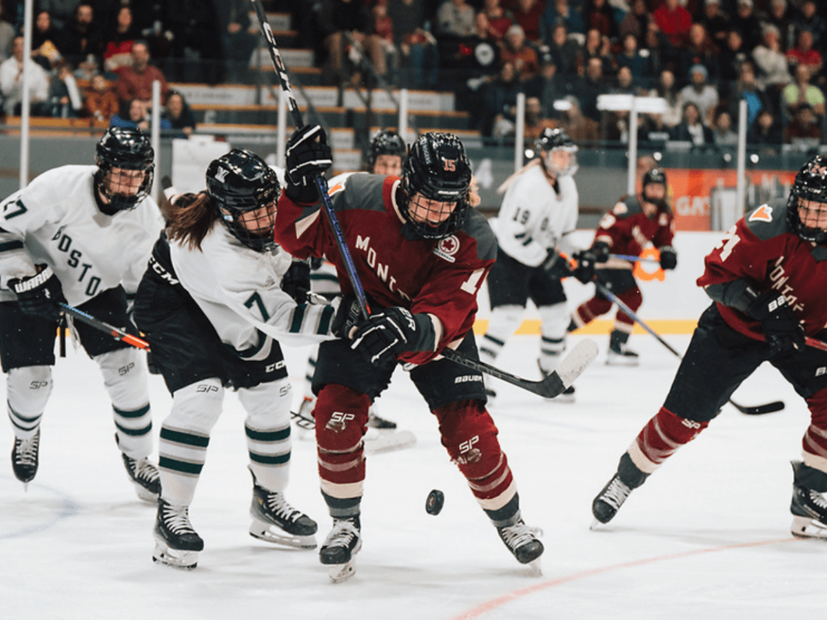 Morin (left in white) reaches around Murphy (right in maroon) to try to get the puck, which is bouncing in front of her.
