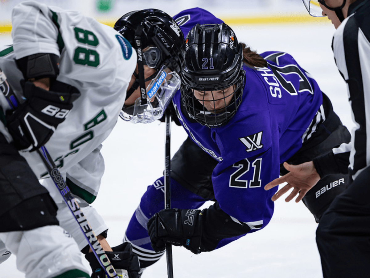 Tapani (left in white) takes a face off against Schepers (right in purple). They're both crouched with their sticks down.