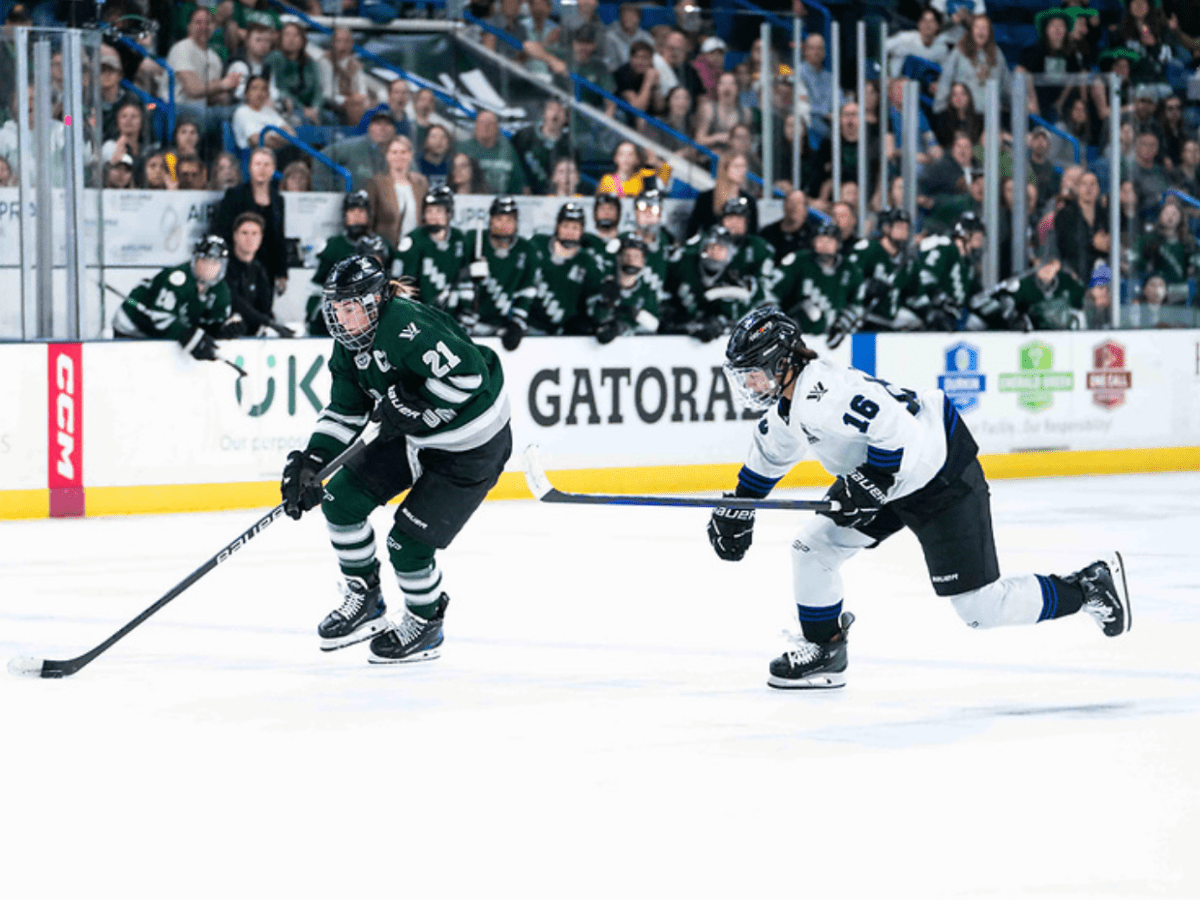 Knight (left in green) enter the zone and drives the net with the puck while Jaques (right in white) chases.