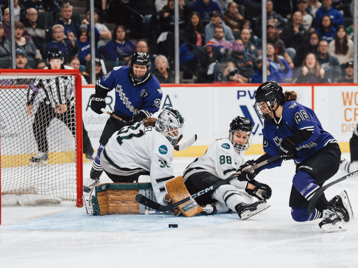 Cava (right in purple) is on her knee about to shoot, while Frankel is reaching from her knees and Tapani lays on the ice.