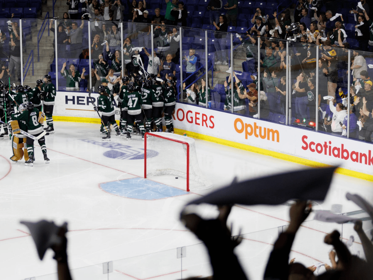 A wide shot of Boston celebrating with a group hug in the corner, while fans cheer in the stands all around them.