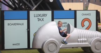 A little boy in a Monopoly car.