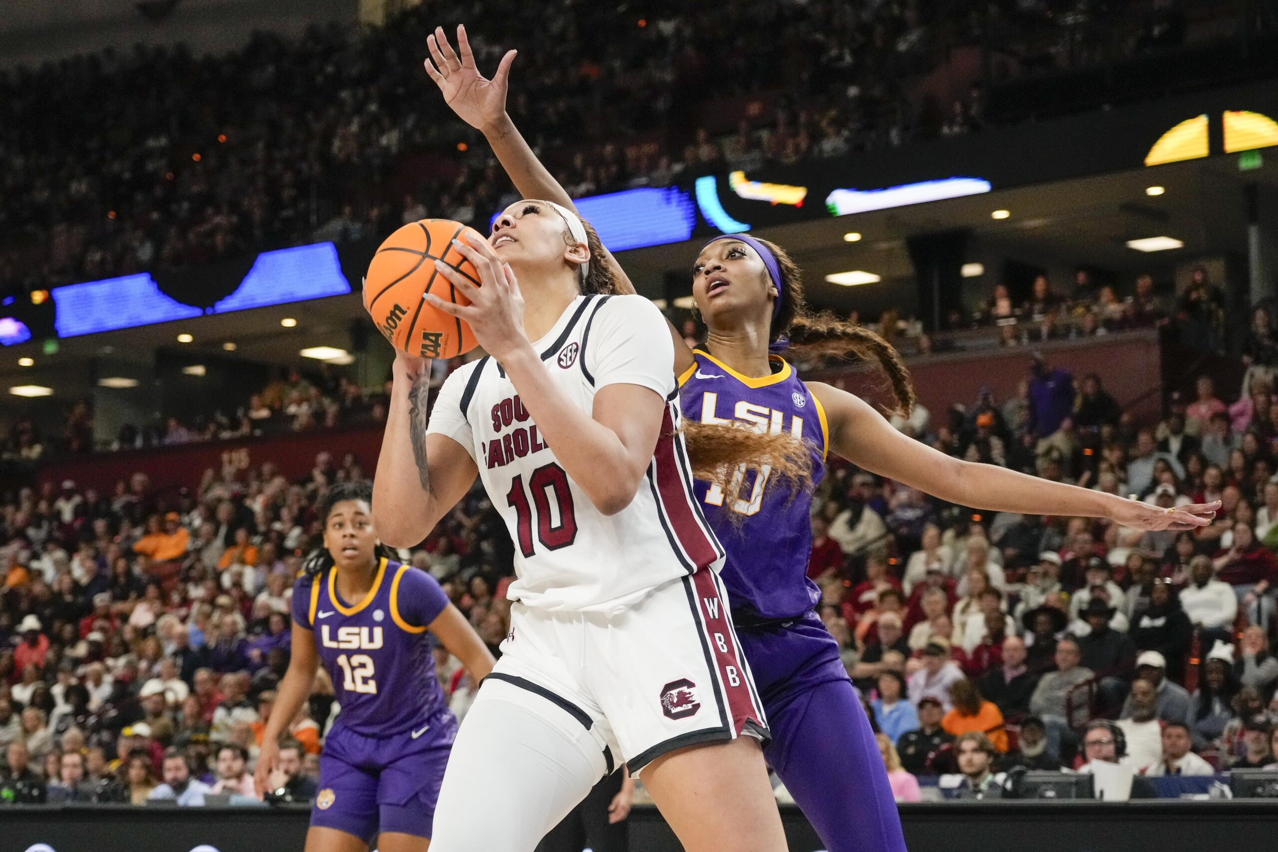 South Carolina center Kamilla Cardoso holds the ball with two hands as she looks to go up for a shot. LSU forward Angel Reese extends her right arm over Cardoso's head to contest the shot.