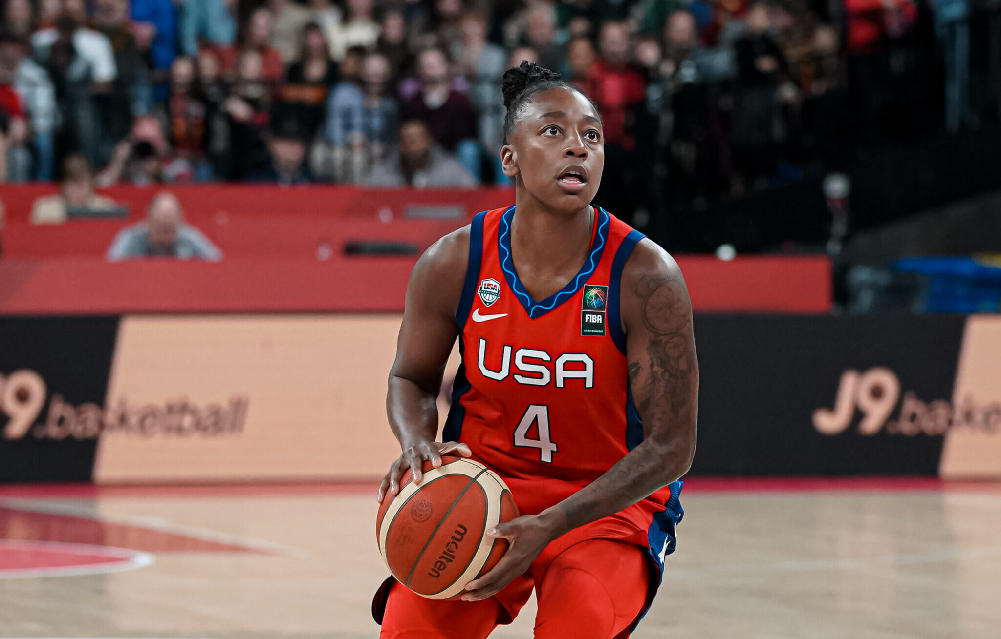 Jewell Loyd wears a red USA jersey, No. 4, and looks up, basketball in hands, to take a shot.