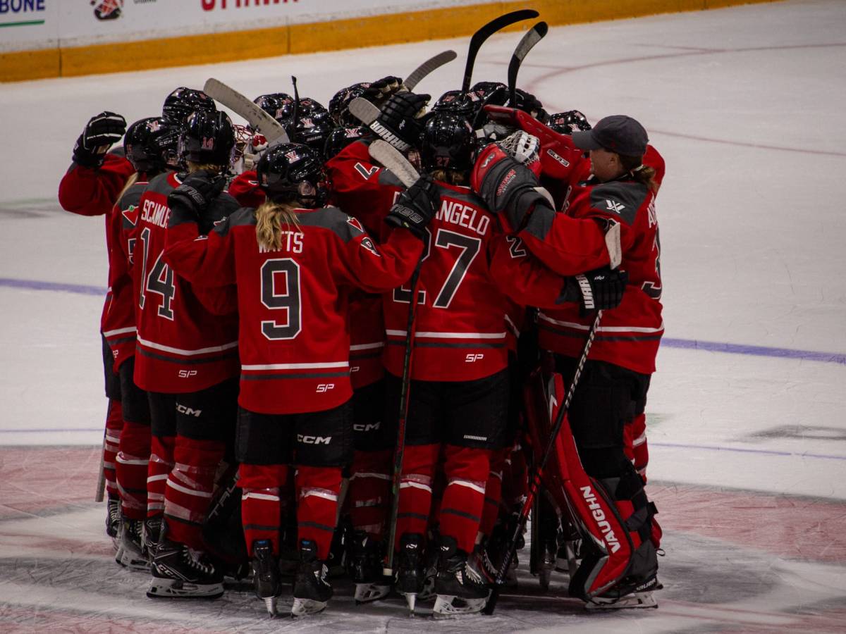 PWHL Ottawa does a group hug at centre ice.
