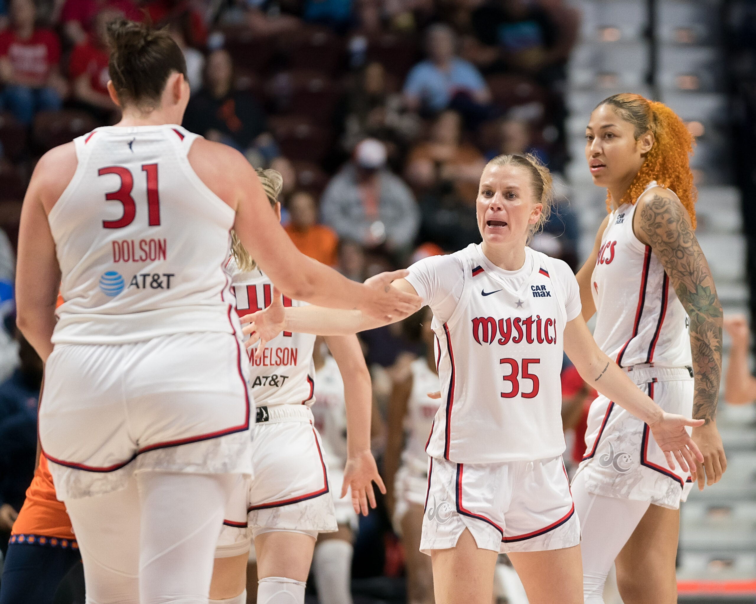 Washington Mystics guard Julie Vanloo reaches her right arm out to the side to high-five center Stefanie Dolson, who is walking toward her.