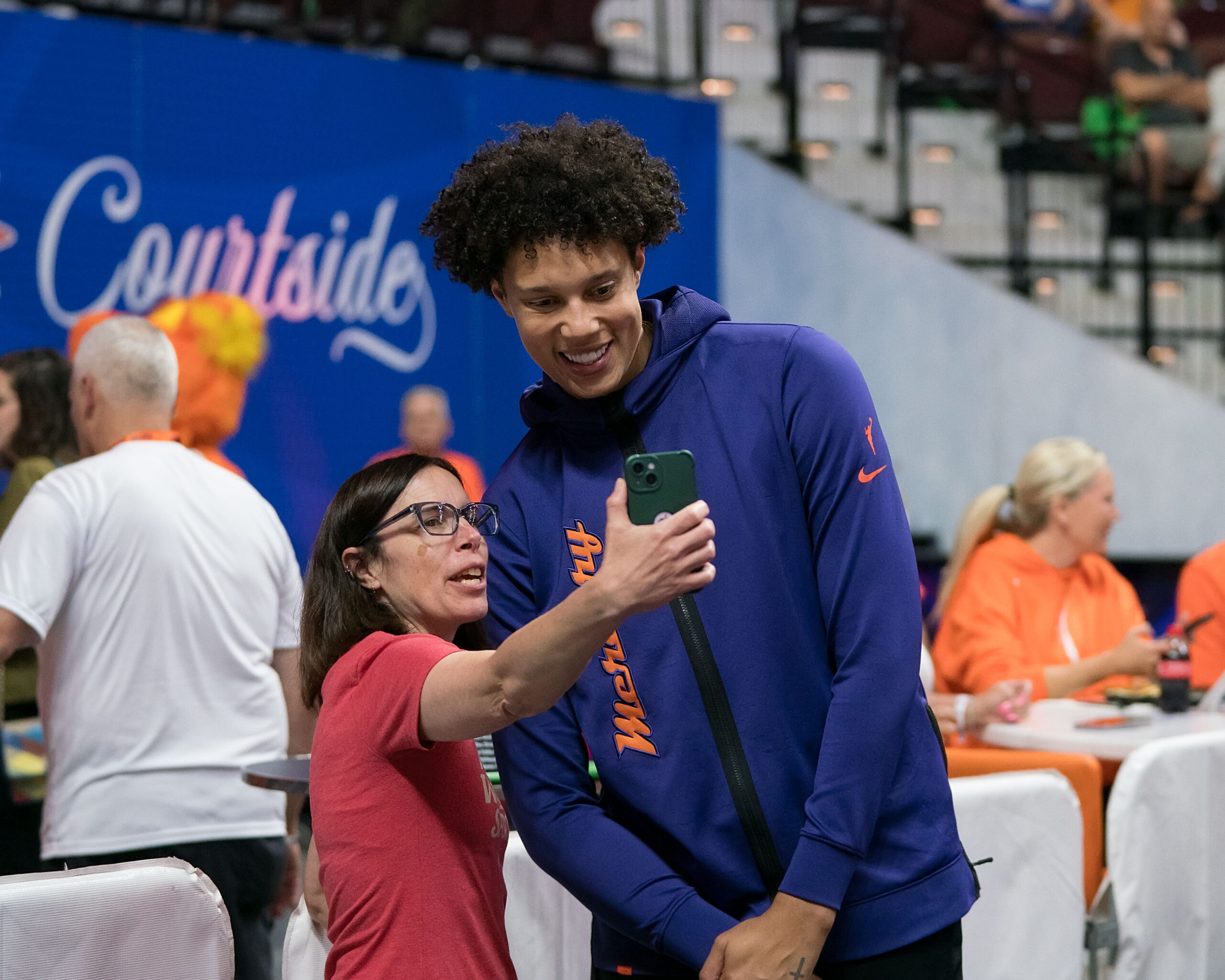 Phoenix Mercury center Brittney Griner smiles as a fan holds up a phone to take a selfie with her.