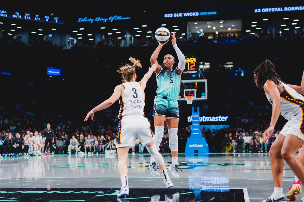 New York Liberty forward Kayla Thornton shoots a jump shot with her right hand from near the free-throw line. Indiana Fever guard Kristy Wallace extends her right hand toward Thornton to try to contest the shot.