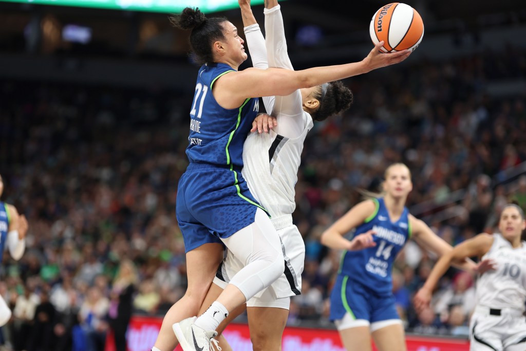 Las Vegas Aces wing Alysha Clark has her arms straight up as Minnesota Lynx guard Kayla McBride makes contact while trying to shoot a right-handed layup.