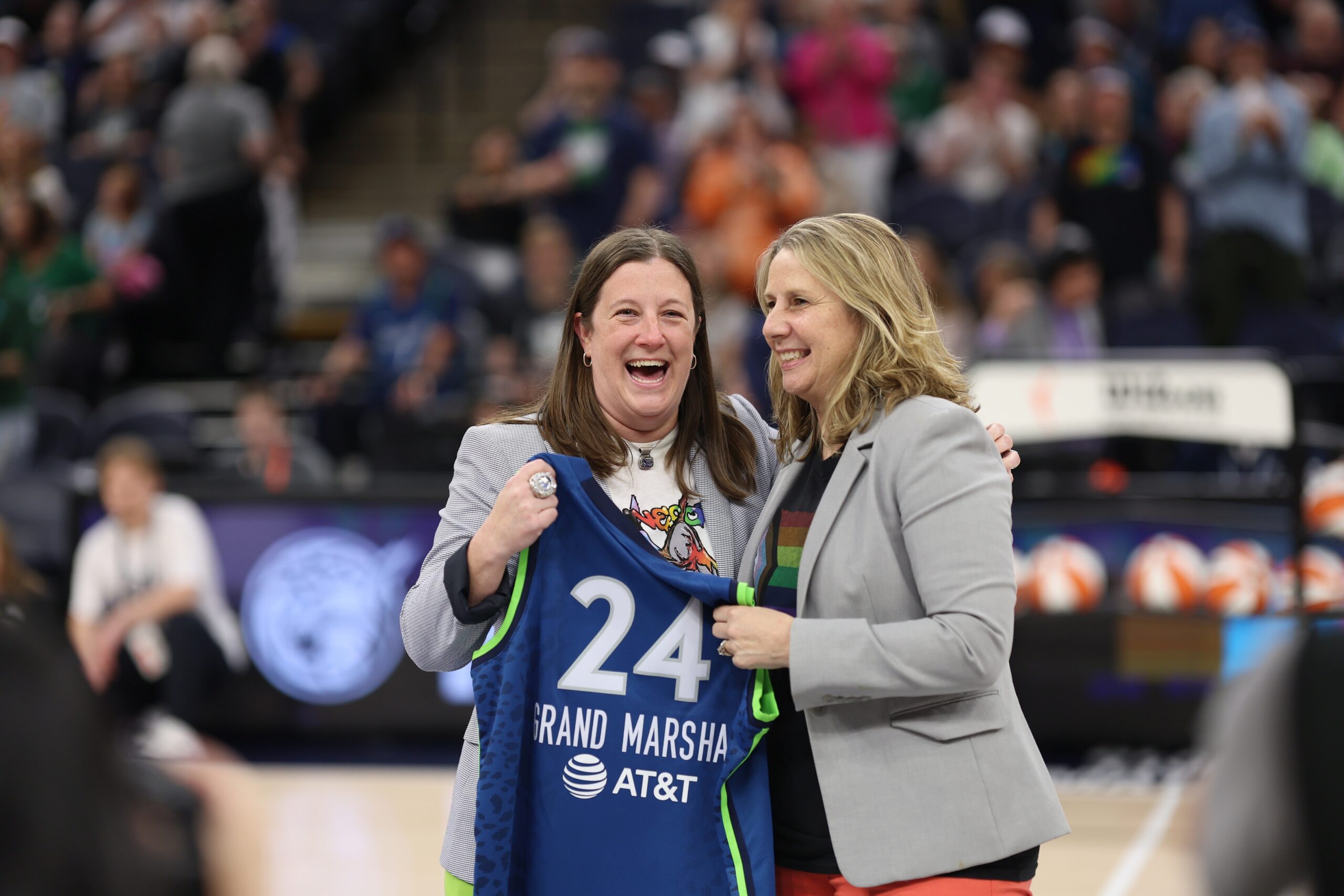 Minnesota Lynx president of business operations Carley Knox and head coach Cheryl Reeve smile and pose for a photo with a custom Lynx jersey made for Knox. The jersey reads "Grand Marshal" with the number 24.