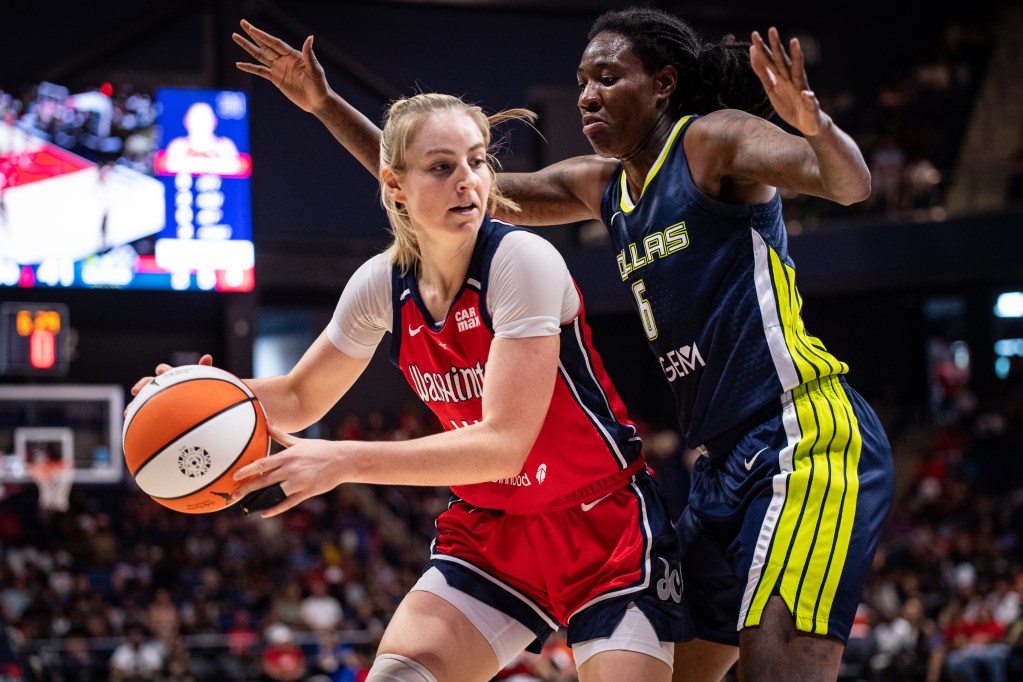 Washington Mystics wing Karlie Samuelson holds the ball with both hands as Dallas Wings forward Natasha Howard pressures her. Samuelson has a black wrap on her left ring finger.