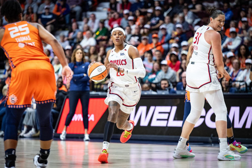 Washington Mystics guard Brittney Sykes dribbles the ball with her right hand. Center Stefanie Dolson stands on the perimeter, facing the opposite way but turning her head to watch Sykes.