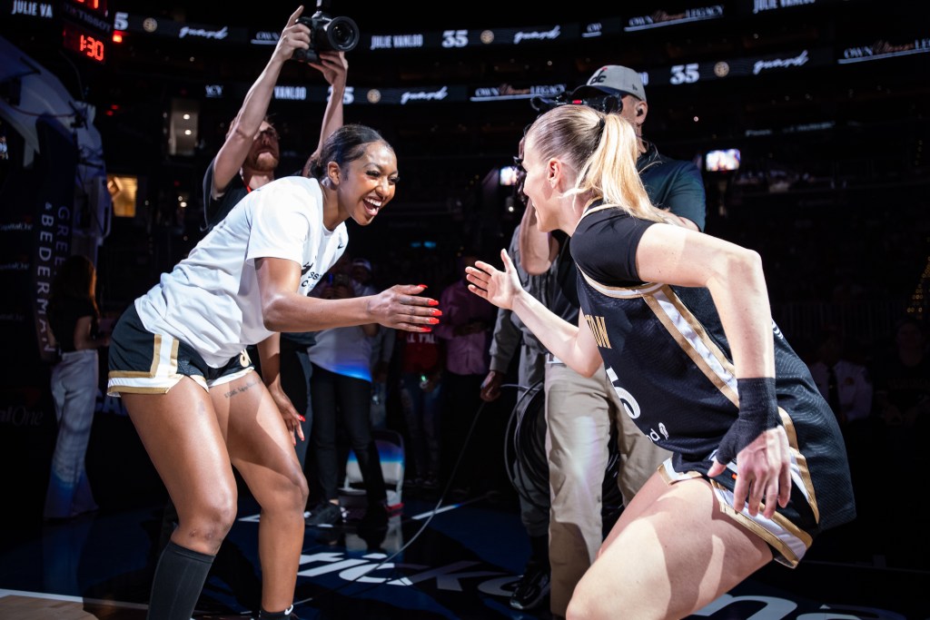 Washington Mystics wing DiDi Richards and point guard Julie Vanloo bend their knees, face each other and slap their right hands together.