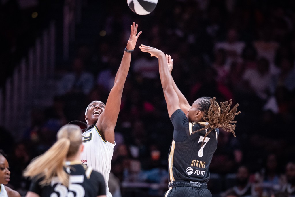Washington Mystics guard Ariel Atkins shoots a jump shot. The ball has barely left Atkins' hand, visible just above the outstretched left arm of Chicago Sky center/forward Elizabeth Williams.