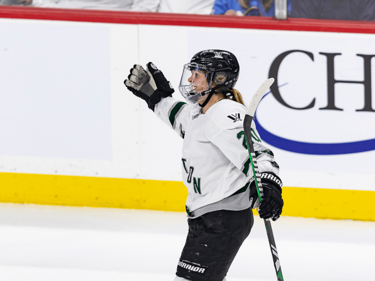 Brandt extends her arms in preparation for a celebratory hug following a win. She is wearing a white away uniform.