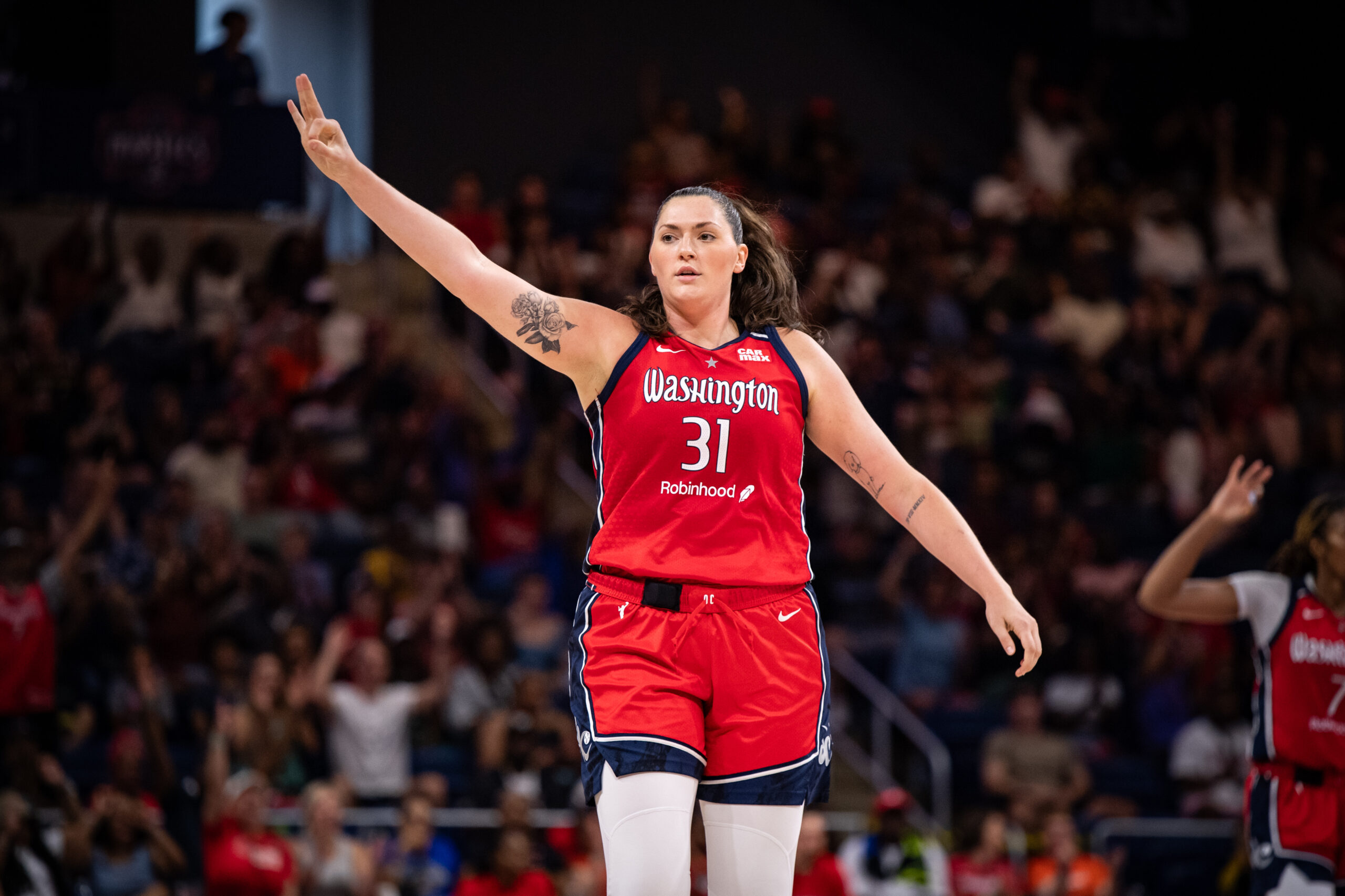 Washington Mystics center Stefanie Dolson holds out her hand with three fingers up to celebrate hitting a 3-pointer in a WNBA game