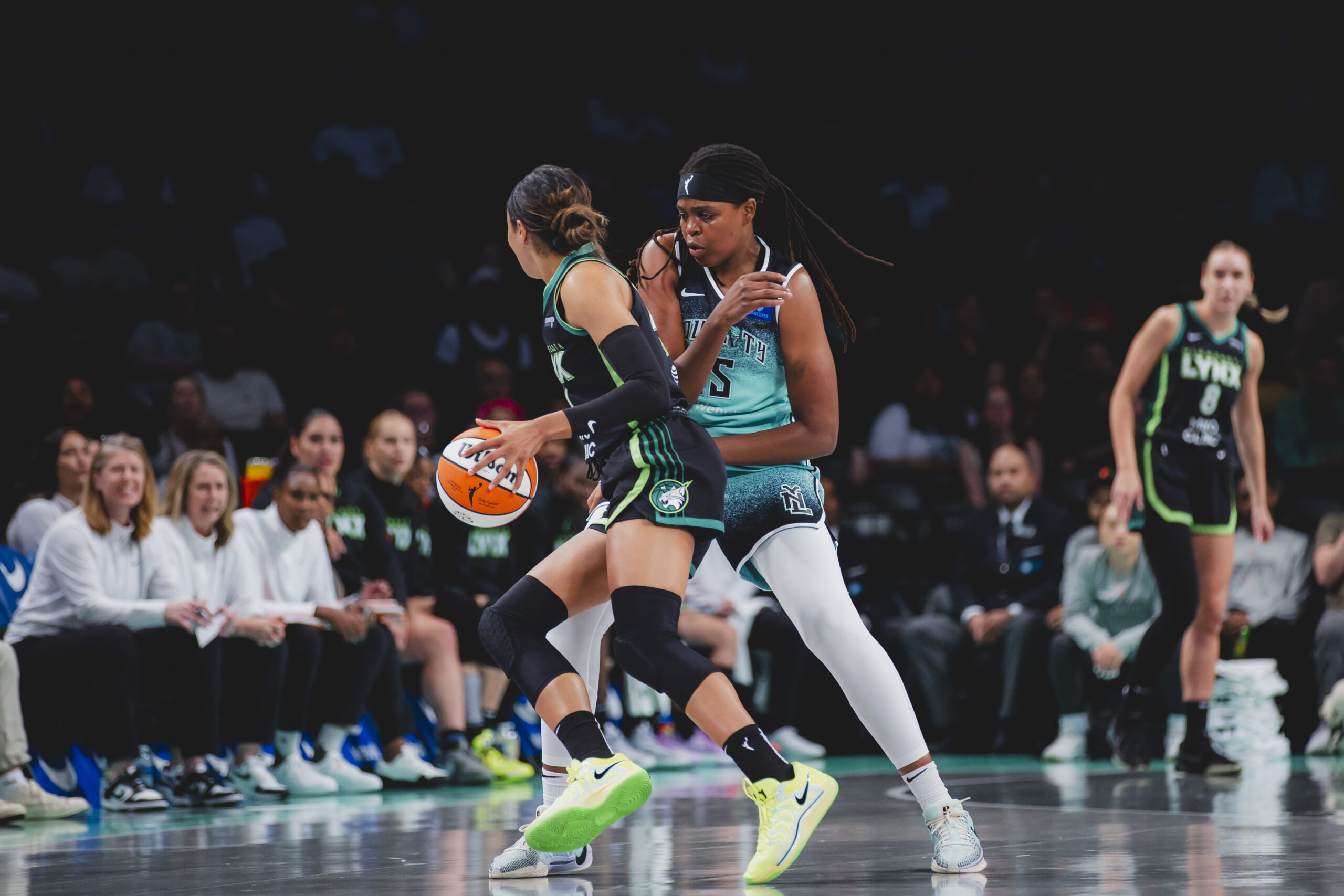 New York Liberty center Jonquel Jones slides her feet laterally to defend Minnesota Lynx forward Napheesa Collier as Collier drives with her left hand.