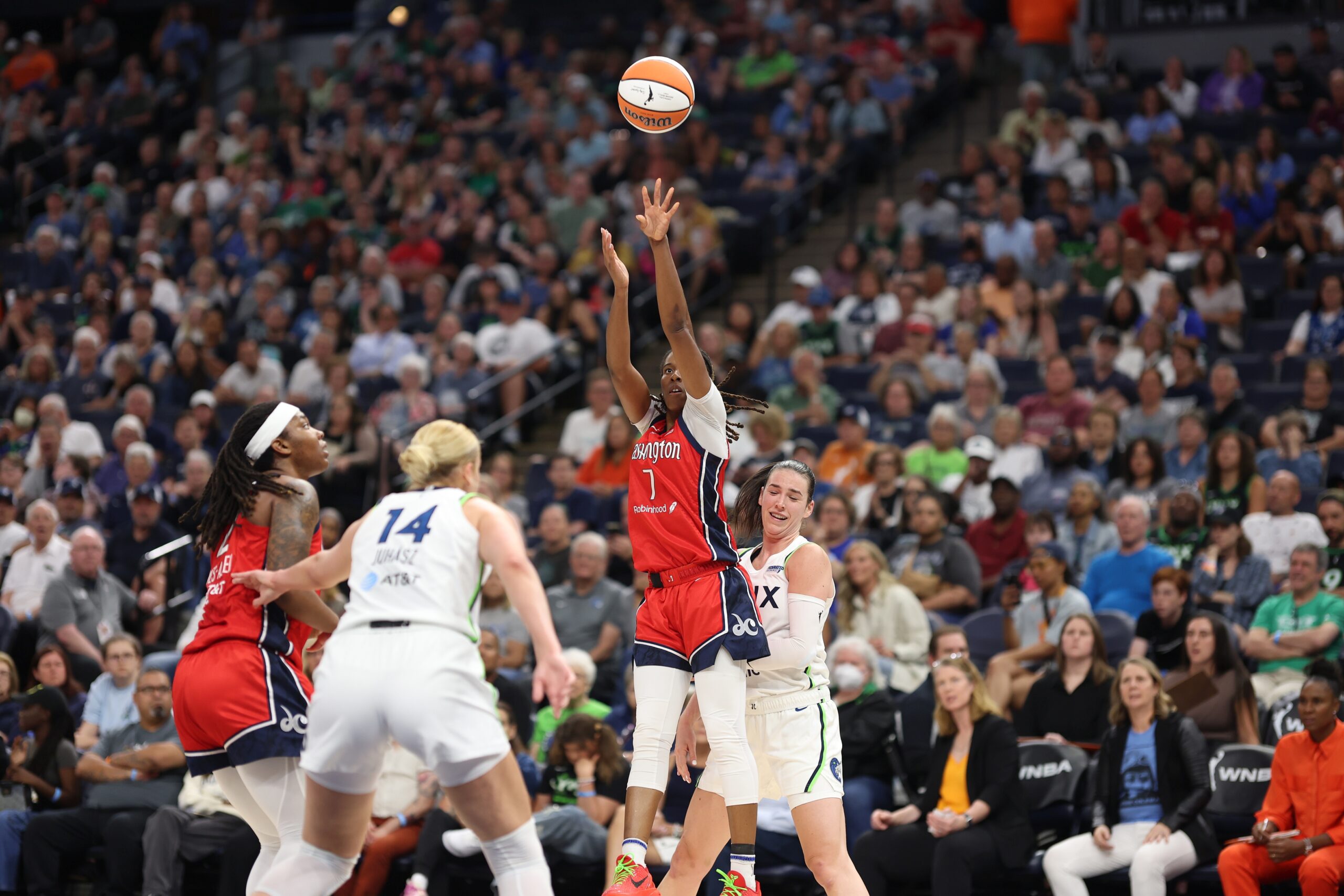 Washington Mystics guard Ariel Atkins shoots a left-handed jump shot as a Minnesota Lynx defender tries to avoid making contact from behind.