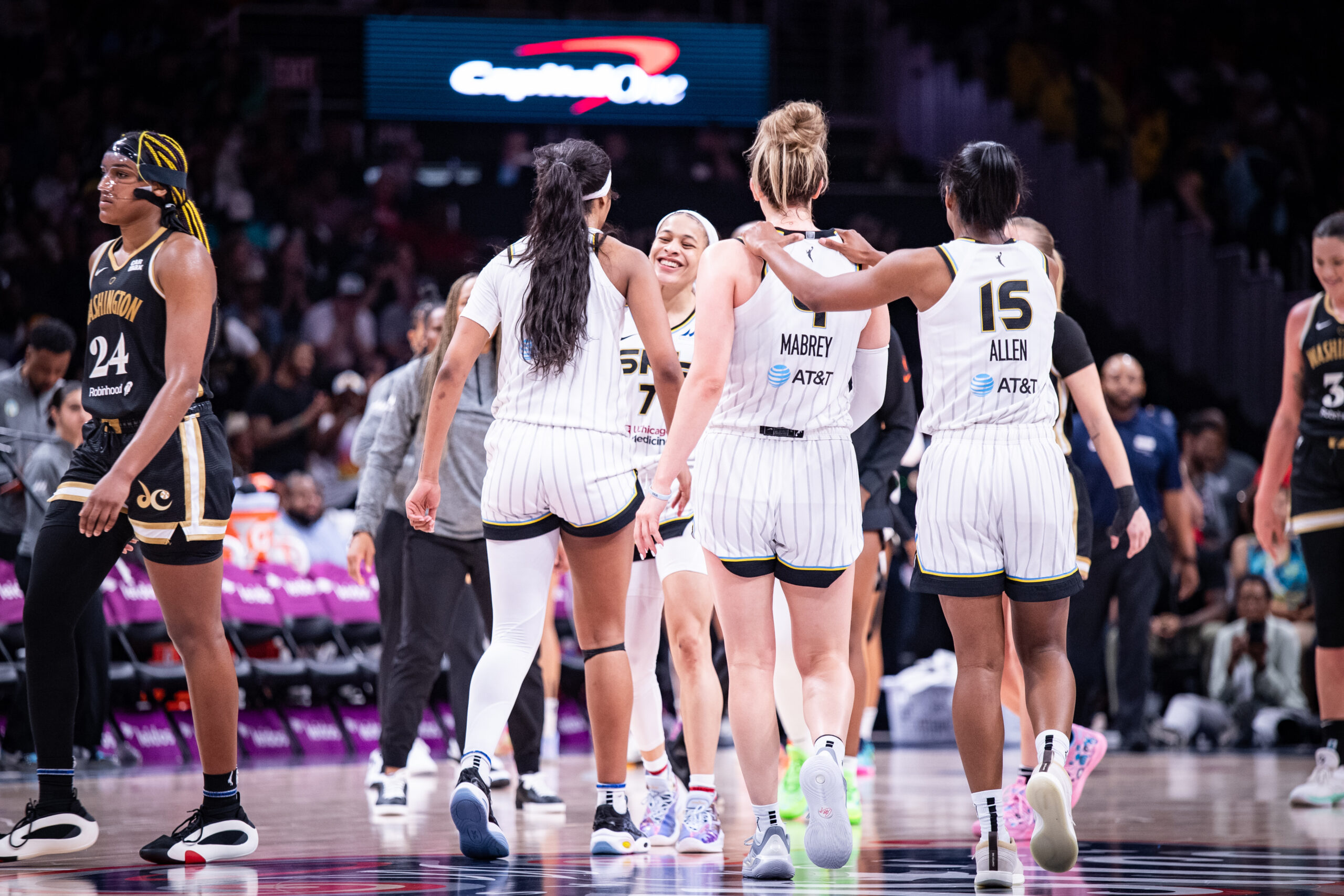 Chicago Sky guard Lindsay Allen puts her hands on the shoulders of teammate Marina Mabrey as they walk to the bench during a stoppage in play. Both players are shown from behind.