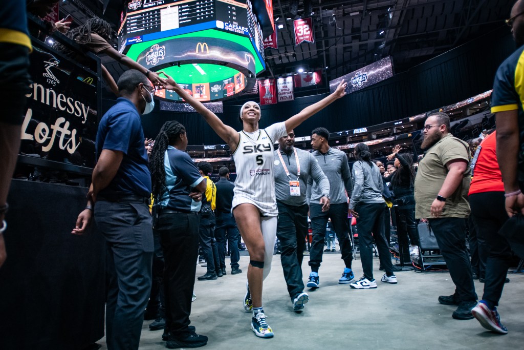 Chicago Sky forward Angel Reese smiles and raises arms towards fans