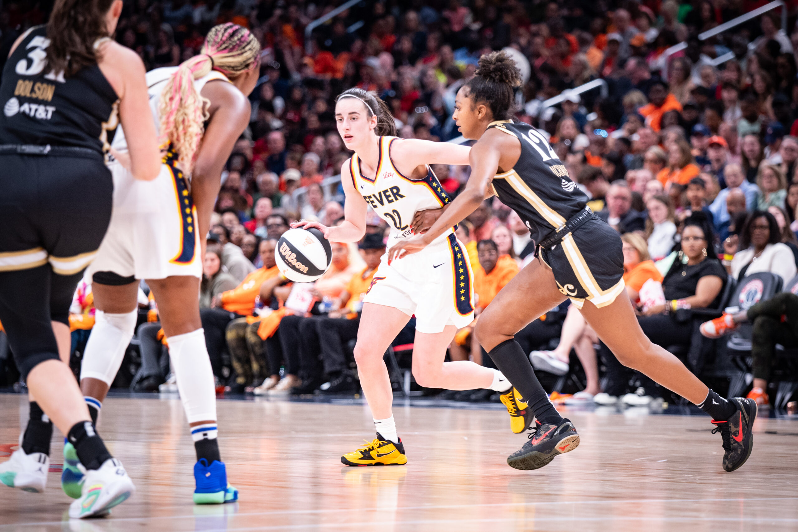 Indiana Fever Caitlin Clark dribbles with her right hand as wing DiDi Richards chases her.
