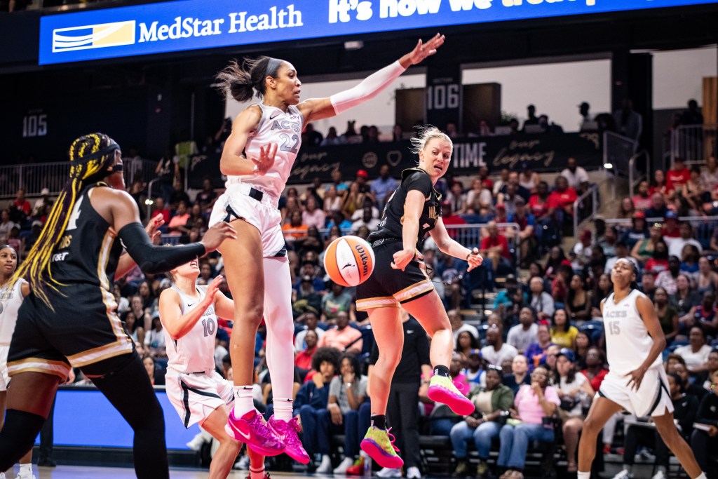 Washington Mystics point guard Julie Vanloo is shown in midair, throwing a pass behind her back with her right hand to forward Aaliyah Edwards.