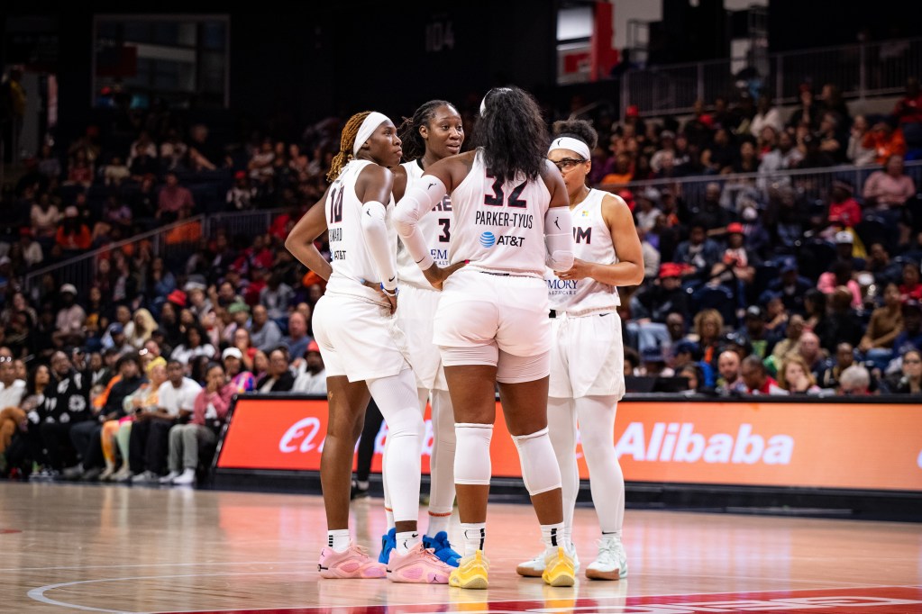 Four Atlanta Dream players huddle near the free-throw line.