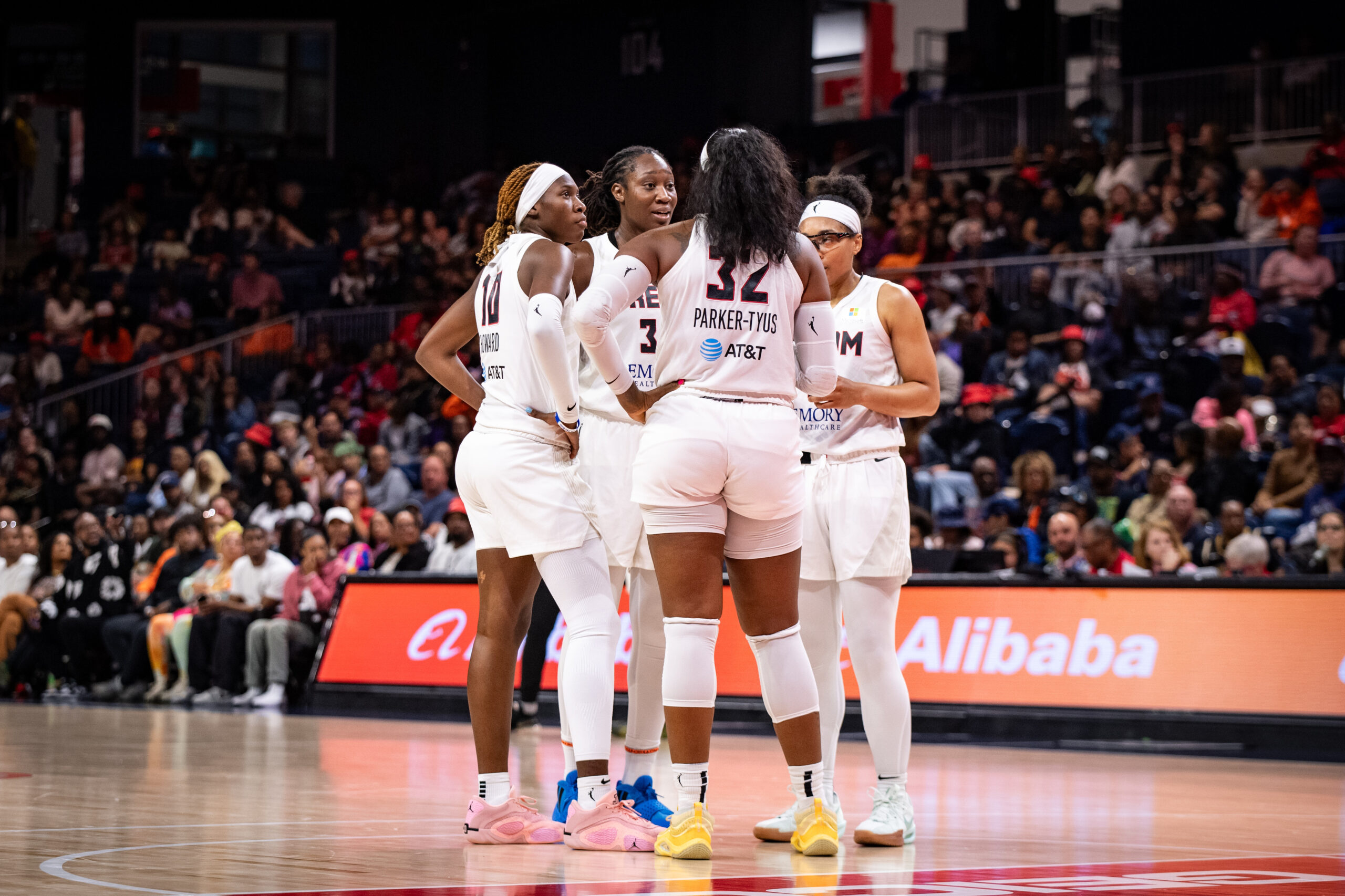 Four Atlanta Dream players huddle near the free-throw line.