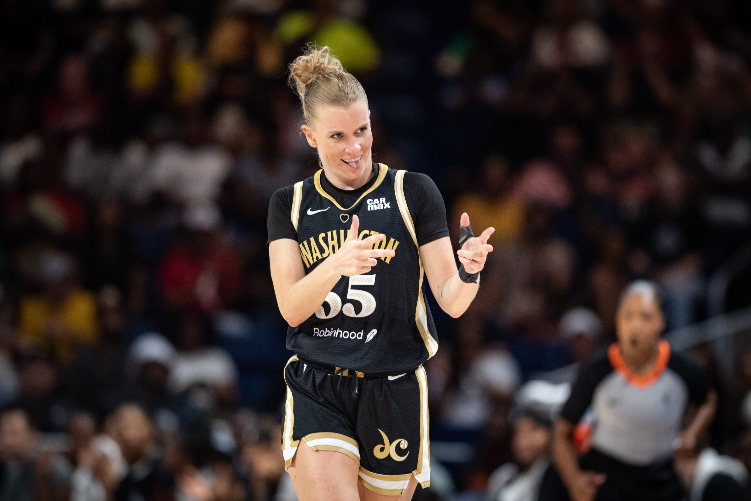 Washington Mystics point guard Julie Vanloo smiles, sticks her tongue out, and holds both hands with her thumbs and two fingers sticking out.