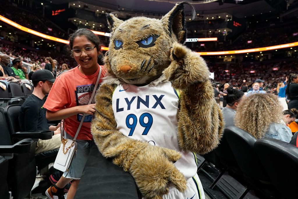 A young fan poses with the Minnesota Lynx mascot Prowl, who is wearing a No. 99 Lynx jersey